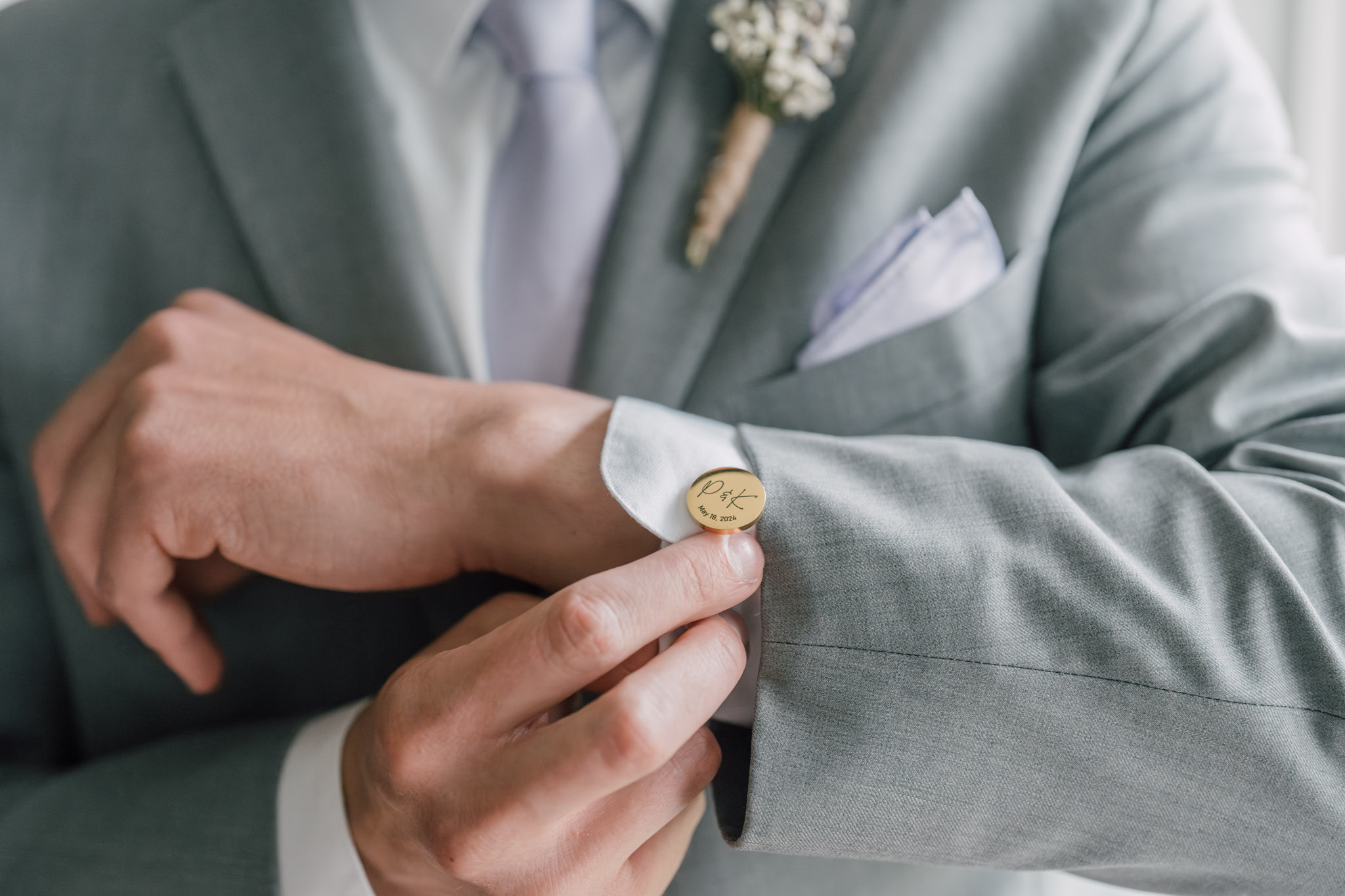 A groom fastening a gold cufflink in Leicester, Massachusetts