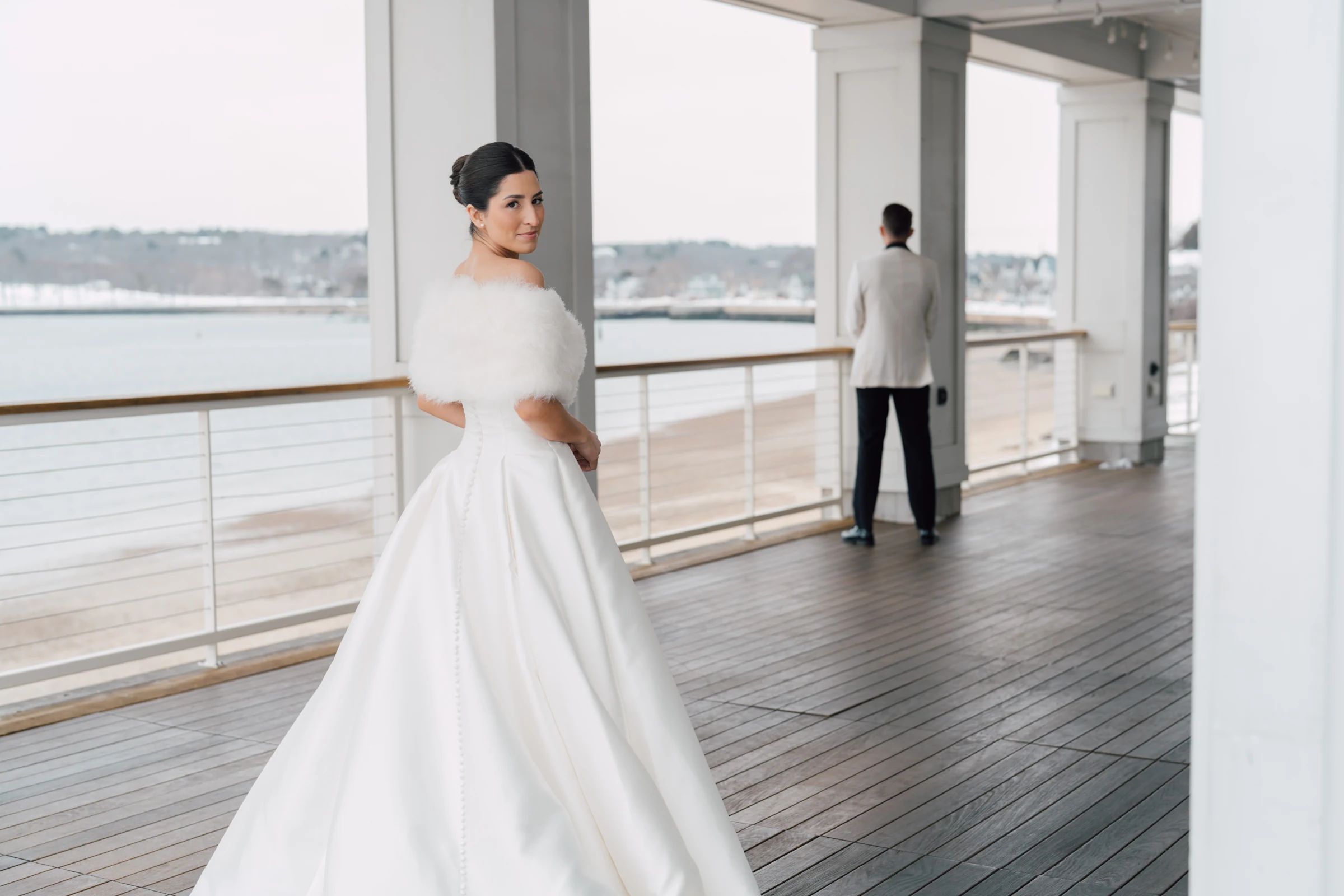 A bride approaching her groom on a waterfront porch at Beauport Hotel, Gloucester, Massachusetts