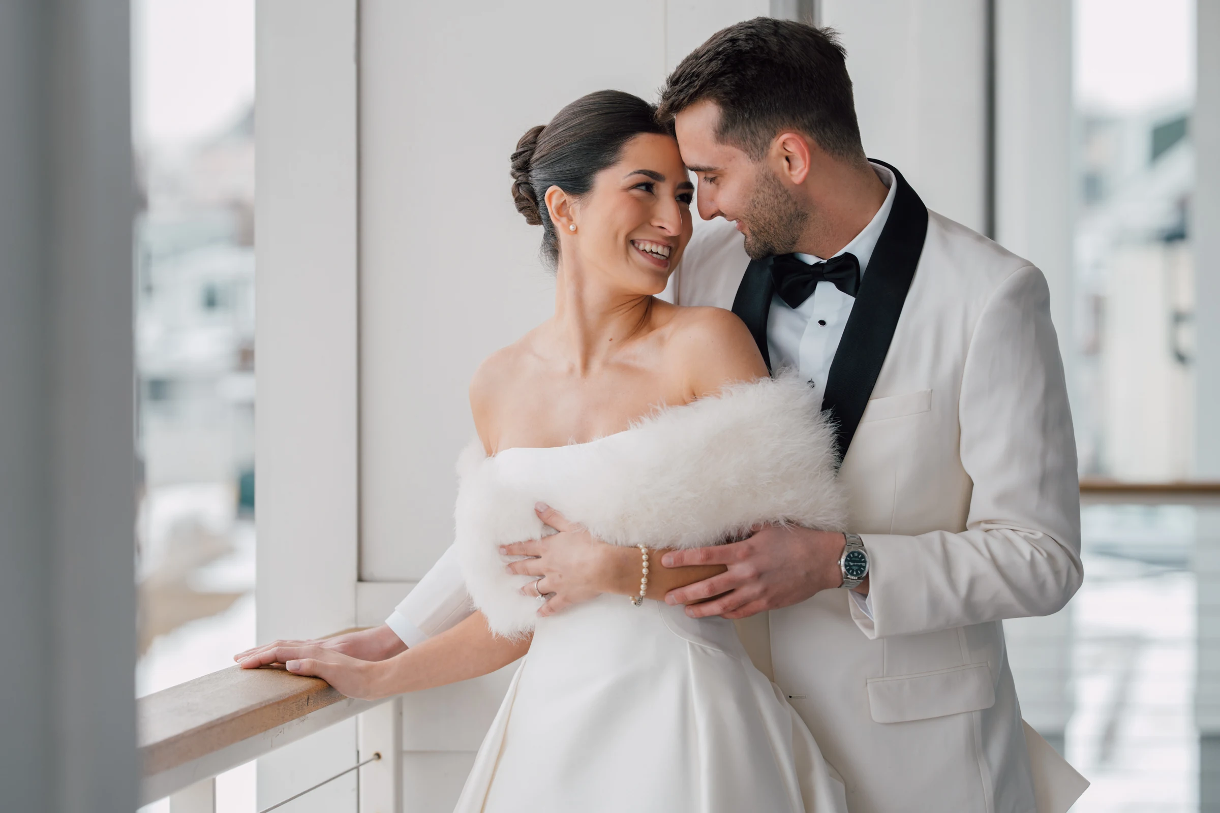 Newlyweds leaning together on a waterfront porch at Beauport Hotel, Gloucester, Massachusetts