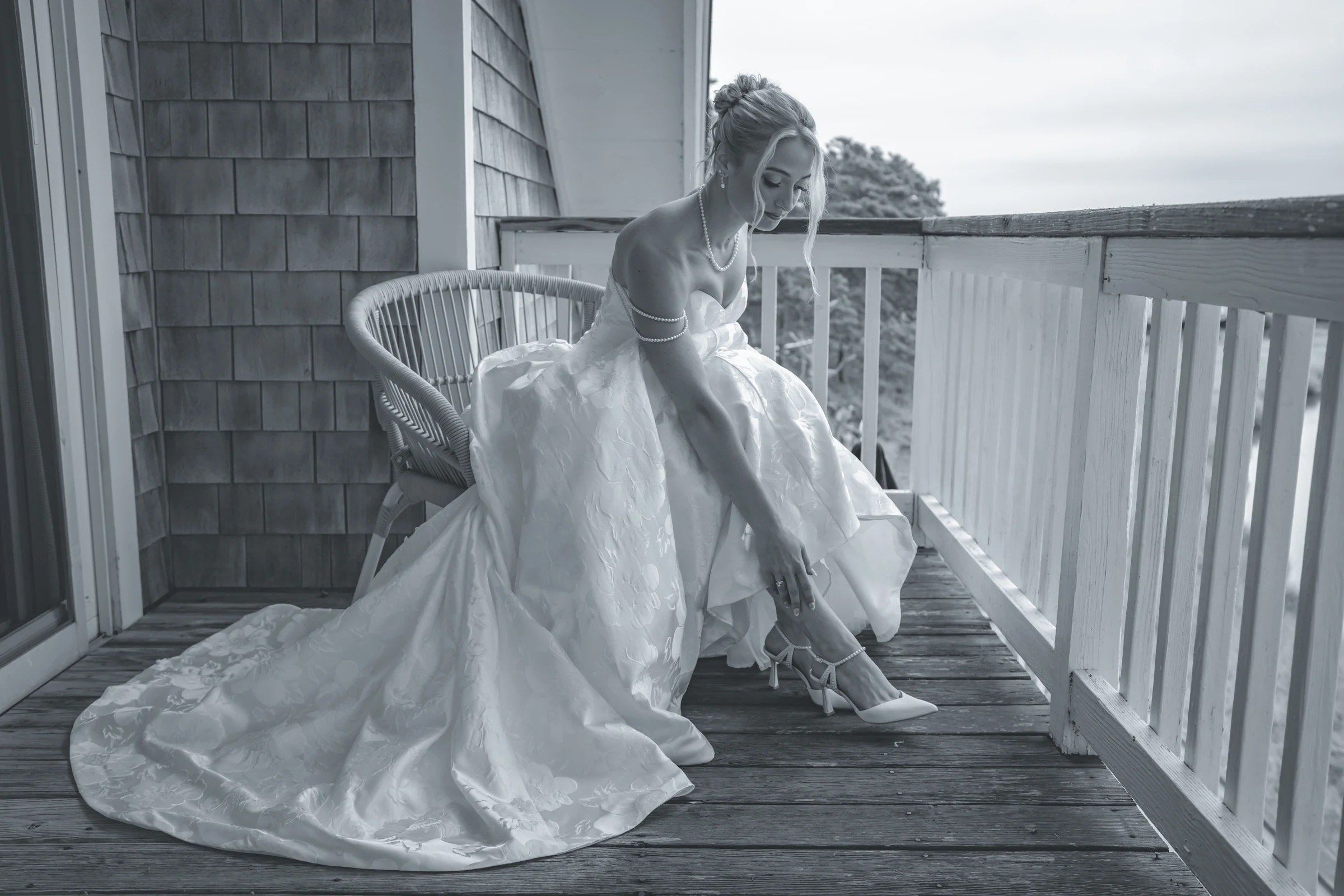 A bride adjusting her shoe on a wooden porch at Wequassett Resort, Harwich, Massachusetts