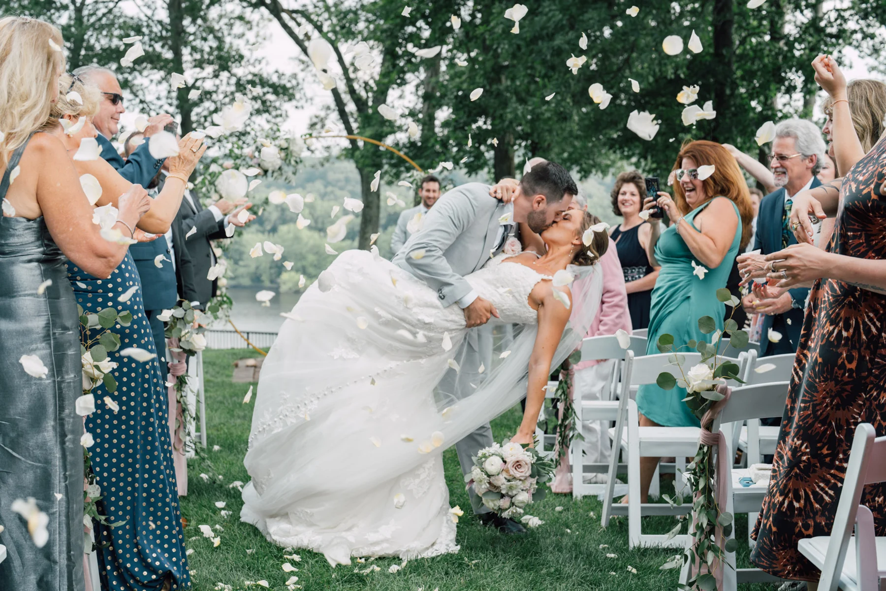 Newlyweds sharing a dip and kiss beneath falling flower petals at Saint Clements Castle, Portland, Connecticut