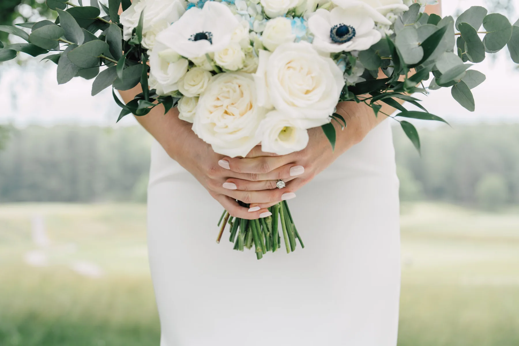 A bride holding a white rose and anemone bouquet at Worcester Country Club, Worcester, Massachusetts